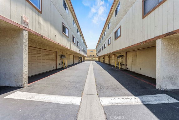 Outdoor parking area between two residential buildings with garages.