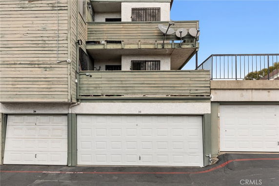 Front view of a multi-story building with wooden balconies and garage doors.