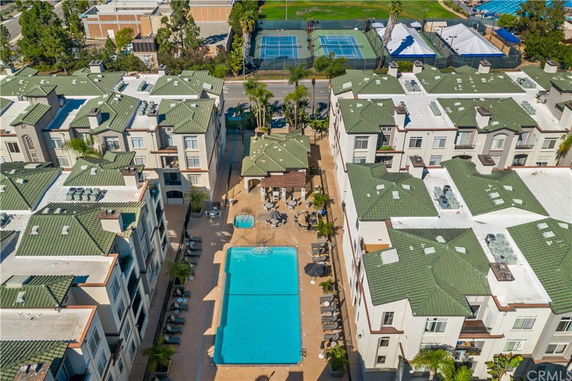 Aerial view of a residential complex with green roofs and a central swimming pool.