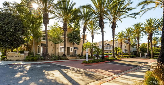 Front view of a residential building with palm trees and a driveway.