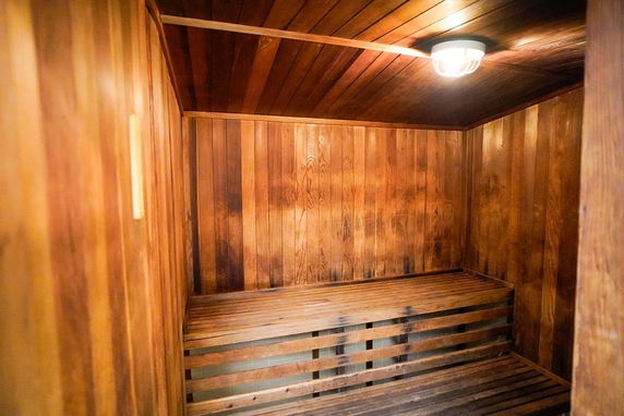 Interior view of a wooden sauna room with a bench and light fixture.