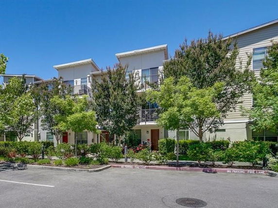 Front view of a multi-story residential building with trees and landscaping in front.