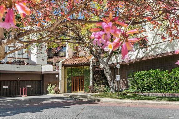 Front view of a building with a garage entrance and flowering trees.