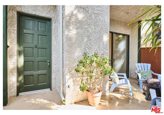 Front view of a house entryway with a green door and outdoor seating area.
