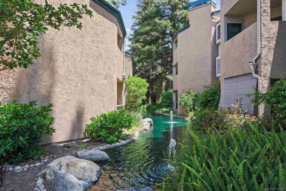 Apartment buildings with a fountain and greenery in between.