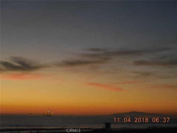 Sunset view over the ocean with oil platforms in the distance.