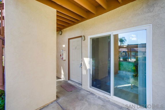 Entrance view of an apartment with a glass sliding door and a single entrance door.