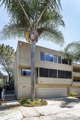 Front view of a multi-story building with a garage and palm trees.