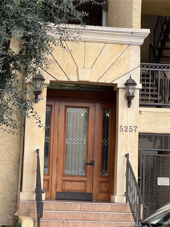 Front view of a building entrance with decorative wooden doors and two lantern-style lights.