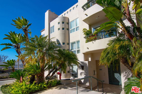 Front view of a multi-story modern building with balconies and large windows.