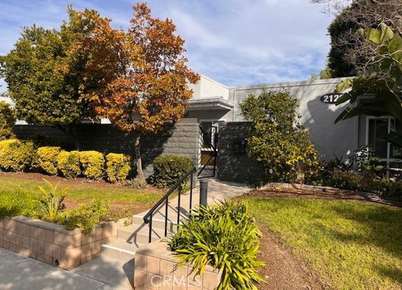 Front view of a single-story building with a brick walkway and surrounding vegetation.