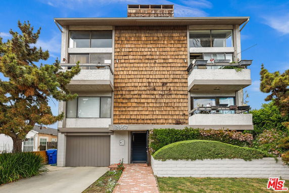 Front view of a multi-story house with wooden shingles and balconies.
