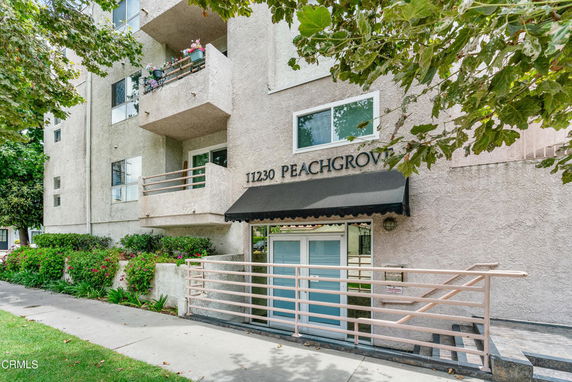 Front view of a multi-story apartment building with balconies and an entrance awning.