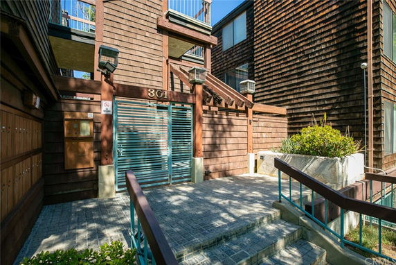 Front view of a building entrance with wooden siding and metal gate.