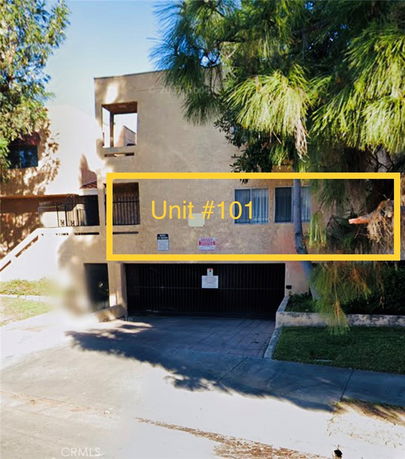 Front view of a building with multiple units and a gated parking area.