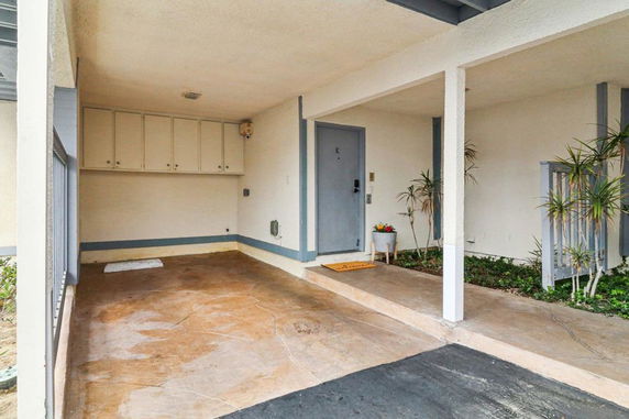 Covered parking area with storage cabinets and a small entryway.
