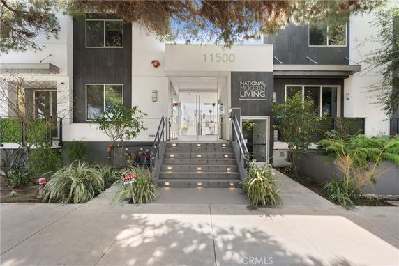 Front view of a modern residential building with stairs leading to the entrance.