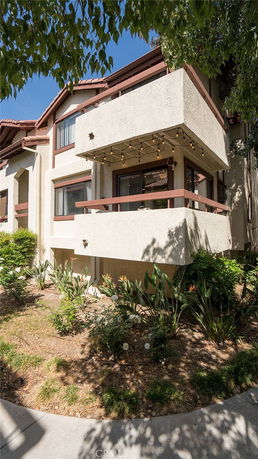 Front view of a multi-story house with a balcony and decorative lights.