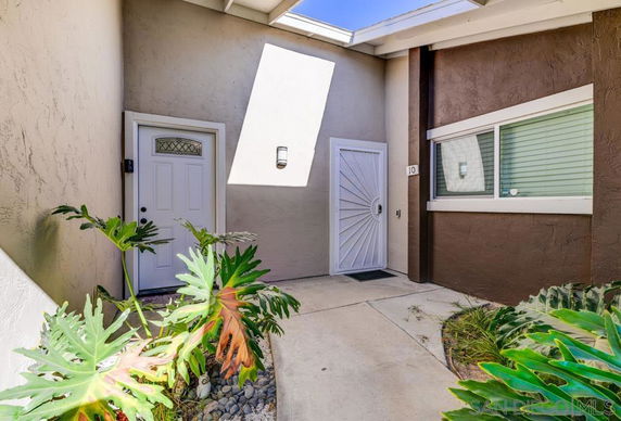 Front view of a house entrance with a white door and adjacent window.