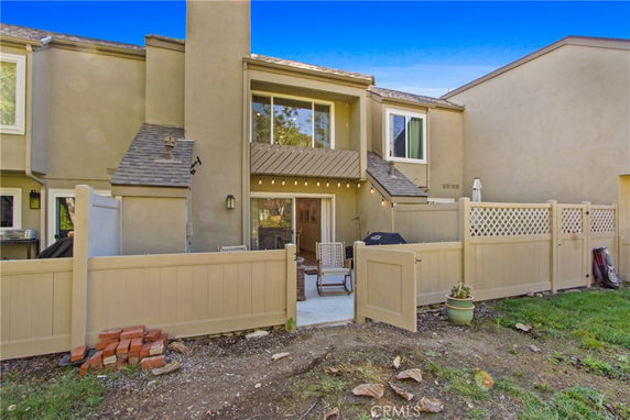 Rear view of a two-story house with a fenced patio area.