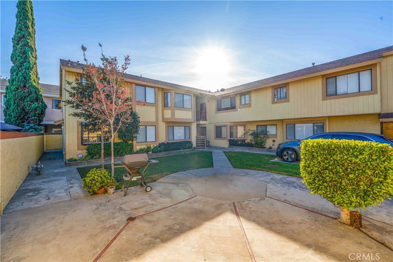 Front view of a two-story residential building with yellow siding and multiple windows.