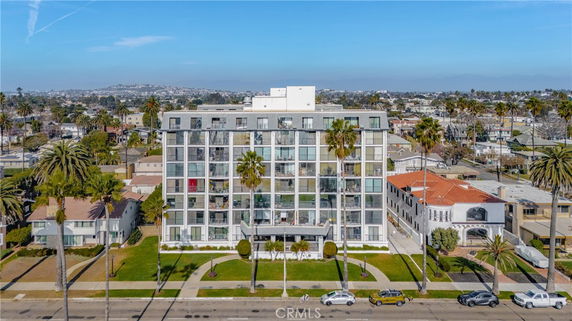 Front view of a multi-story residential building with palm trees lining the entrance.