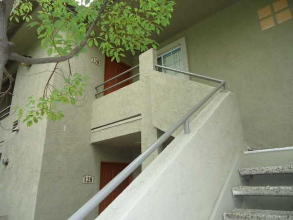 View of a building entrance with stairs leading to a second-story doorway.