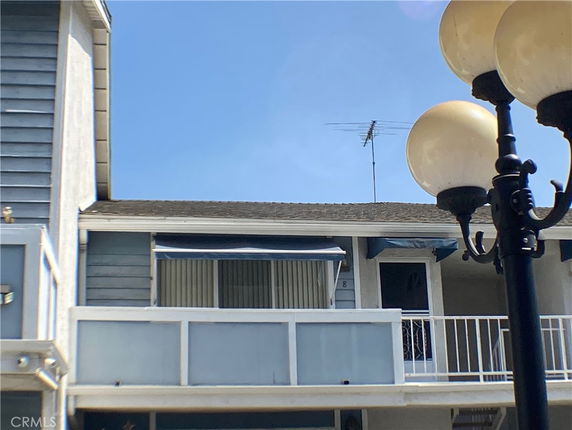 Front view of a building with a balcony and an antenna on the roof.