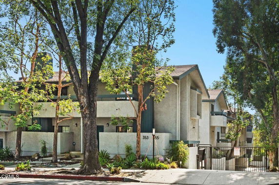 Front view of a multi-story residential building with balconies and a gated entrance.