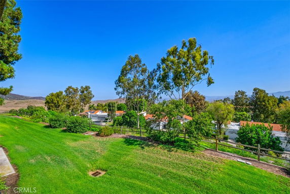 View overlooking a grassy area with trees and parts of rooftops visible in the background.
