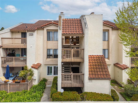 Front view of a three-story apartment building with balconies and tiled roof.