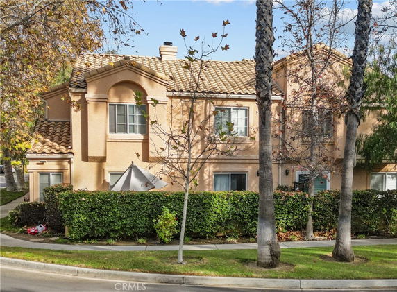 Front view of a two-story house with a tile roof and beige exterior.