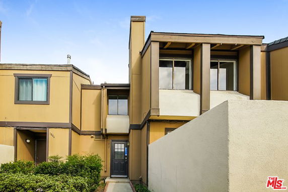 Front view of a multi-story house with a flat roof and beige exterior.