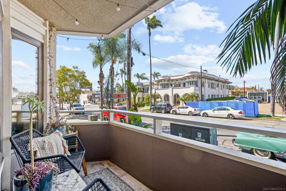 View from a balcony of a residential area with palm trees and parked cars.