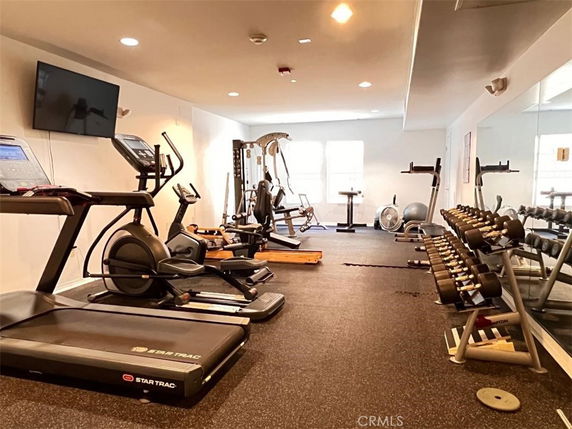 Indoor gym area with exercise equipment and weights.