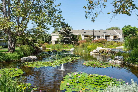 View of building with a pond and garden in the foreground.