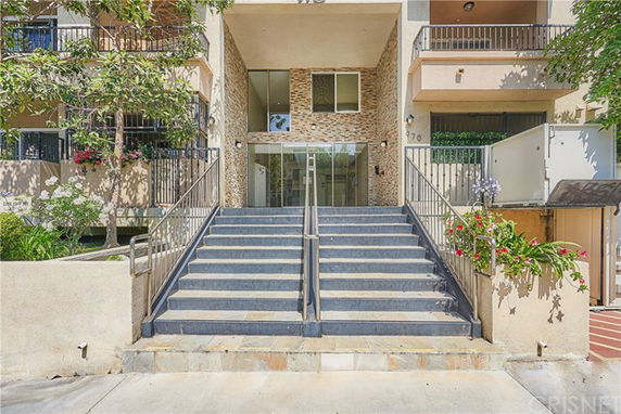 Front view of a multi-story building entrance with stairs leading up to a glass door.