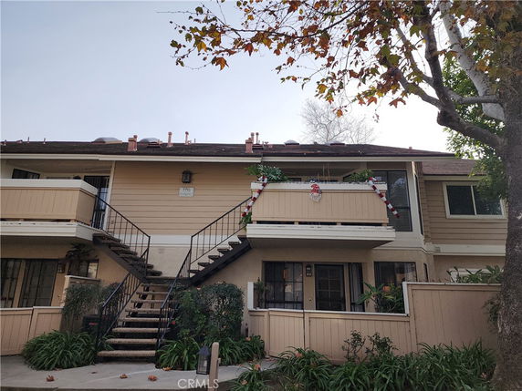 Front view of a two-story residential building with stairs leading to the upper level and decorated balcony.