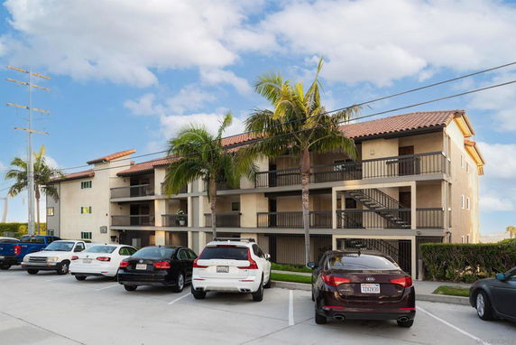 Front view of a three-story apartment building with a parking area.