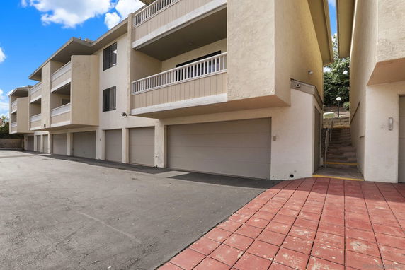 Outdoor parking area in front of a multi-story building with garages.