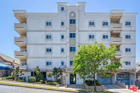 Front view of a multi-story apartment building with balconies and multiple windows.