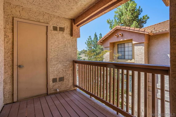 View from a balcony showing the exterior of an adjacent building with stucco walls and a window.