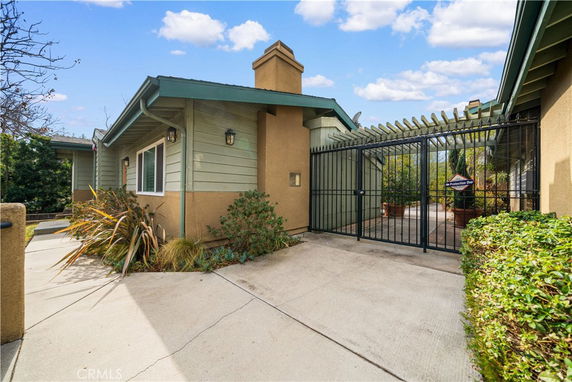 Front view of a house with a gated entrance and a chimney.