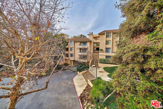 Front view of a multi-story residential building with a sloped roof and balconies.