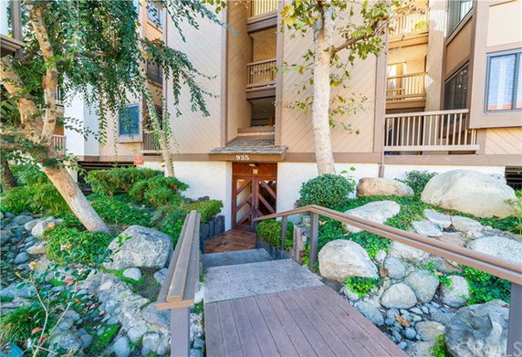 Entrance to a multi-story residential building with a wooden walkway and surrounding landscaping.