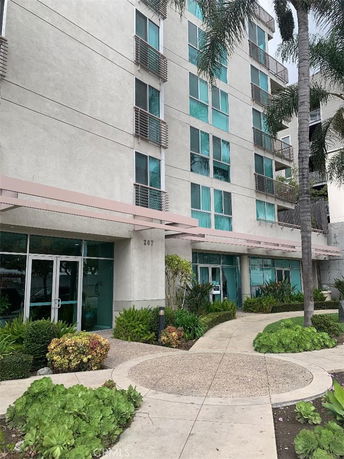 Front view of a multi-story building with glass windows and landscaped entrance.