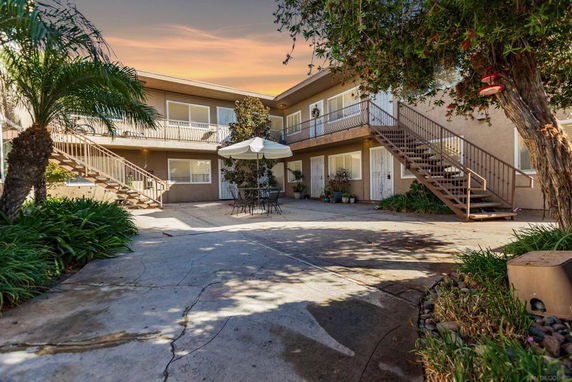 Front view of a two-story residential building with exterior staircases and a courtyard.