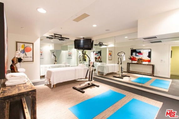 Room with exercise mats, massage table, and wall mirrors.