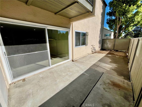 Exterior view of a patio area with sliding glass doors and a small fenced yard.