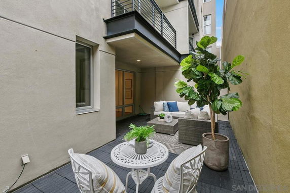 Outdoor patio area with chairs, table, and a potted plant in a narrow courtyard.